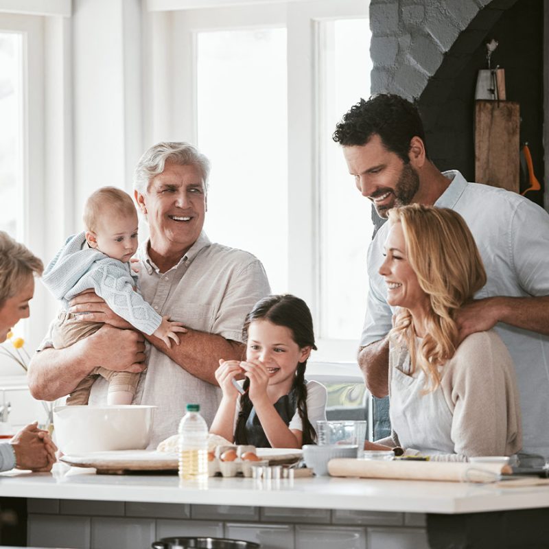 Smiling Grandparents and happy young family in the kitchen