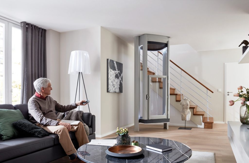 Elderly Man sitting down in living room with a home lift in the background