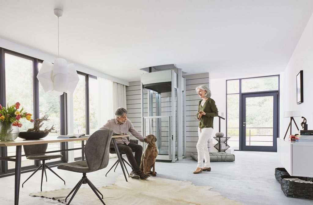 Man patting dog and women next to home lift, holding its lead