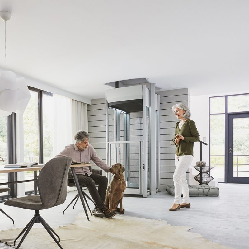 Man patting dog and women next to home lift, holding its lead